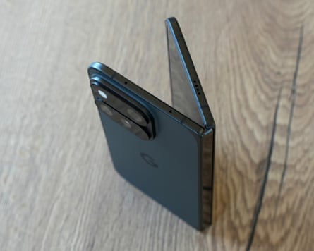 The Google Pixel 11 Pro Fold stood up on a table partially open showing the top edge of the phone and hinge
