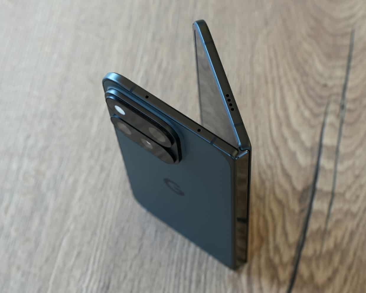 The Google Pixel 11 Pro Fold stood up on a table partially open showing the top edge of the phone and hinge