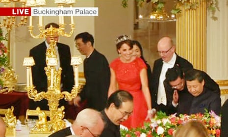 The Duchess of Cambridge in red, takes her seat.