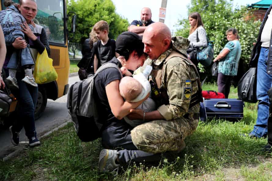 A woman carries a baby as she reacts after getting out of an evacuation convoy from Russian troops’ occupied Kupiansk town.
