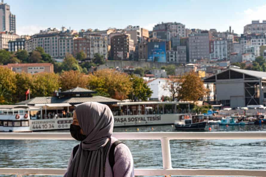 A veiled woman with a mask against a background of water and buildings in Istanbul, Turkey