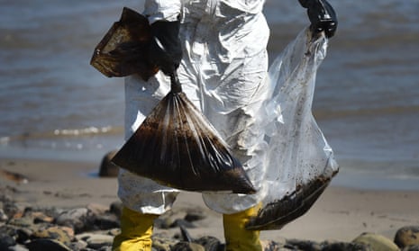 Workers clean oil from the rocks and beach at Refugio state beach in Goleta, California.