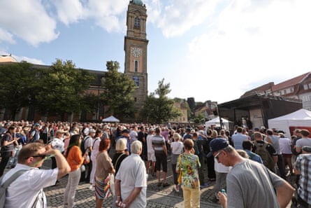 A large crowd stand in a town square