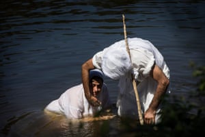 A Mandaean faithful is submerged in the river as part of the baptism