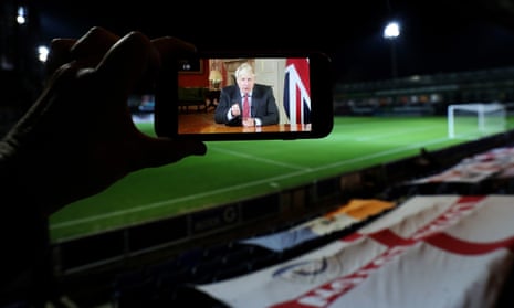 A stream of Boris Johnson’s address to the nation is seen on a phone before Luton Town v Manchester United at Kenilworth Road.