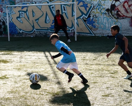Two young boys playing football with an older boy in goal