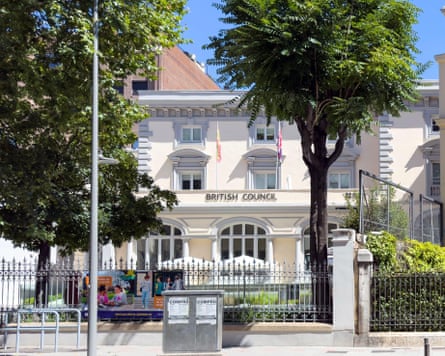 The British Council building in Madrid, a white colonial-style structure framed by trees and an ornate iron fence