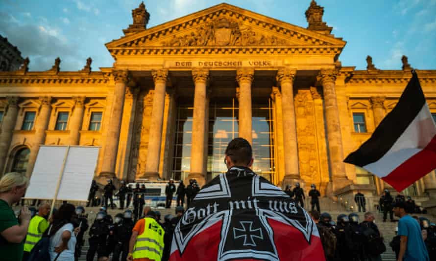 A demonstrator wrapped in a flag of the German empire faces off with riot policemen standing guard in front of the Reichstag building, which houses the Bundestag lower house of parliament, after protesters tried to storm it at the end of a demonstration called by far-right and Covid-19 deniers in 2020.