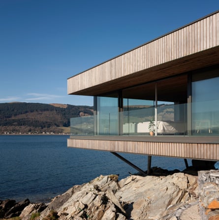 modern house sitting dramatically on rocks over the waterabove