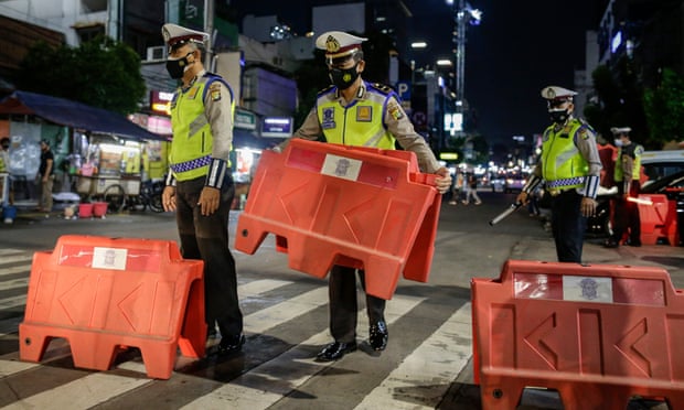 Police officers install road barricades as they close the road following the government’s decision to impose tighter social restrictions amid the rising number of Covid-19 infections in Jakarta