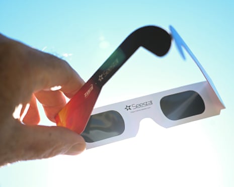 A member of the public holds up a pair of solar eclipse glasses prior to the partial eclipse in Falmouth, England.
