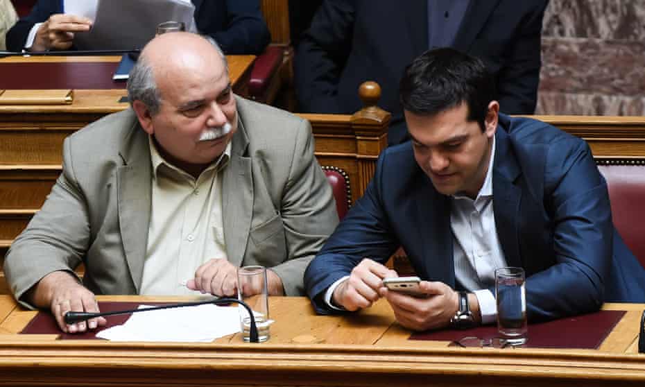 Greek prime minister, Alexis Tsipras (right), uses his phone next to the minister of interior, Nikos Voutsis