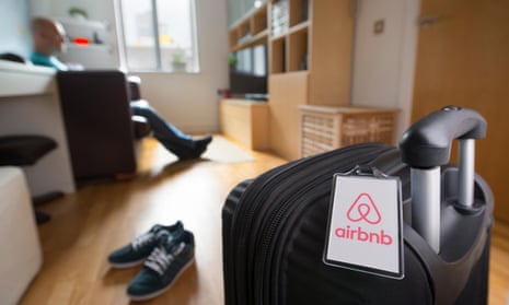 A man sits alone near to a suitcase with an Airbnb branded luggage