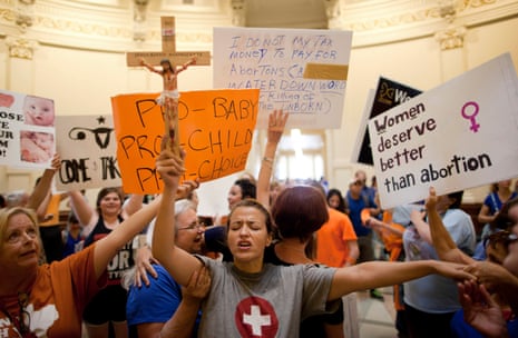 An anti-abortion protester, Katherine Aguilar, holds a crucifix and prays while opponents and supporters of abortion rights gather in the Texas state capitol in July 2013.