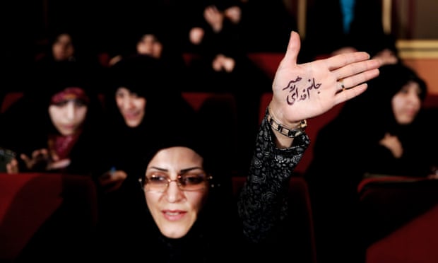 An Iranian raises her palm with writing in Persian