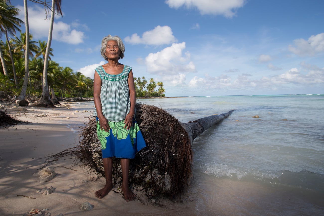 Maria Tekaie stands beside a fallen coconut tree where the sea has washed away the village of Tebontebike on the southern end of Abaiang.