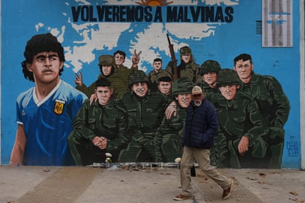 A man walks past a street mural in Buenos Aires depicting Diego Maradona and veterans of the 1982 war between Argentina and the United Kingdom over the Falkland Islands, known in Argentina as the Malvinas