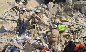 Mound of rubble with people in helmets and hi-vis jackets searching through it