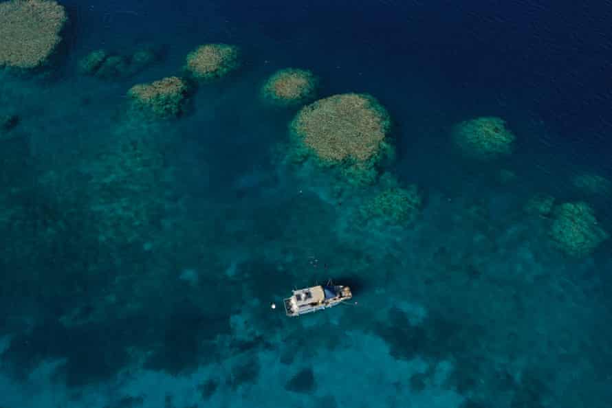 Aerial view of a boat floating above a coral reef.
