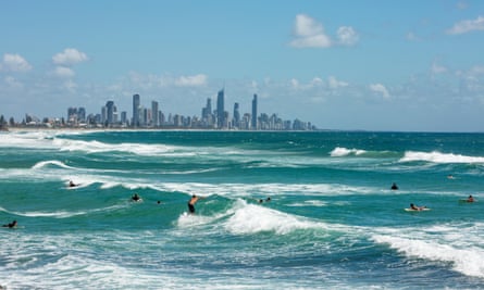 Surfers at Burleigh Heads, with Gold Coast resort of Surfers Paradise in the distance.