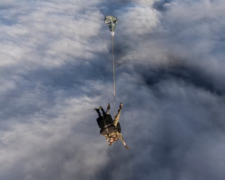 Tandem jumpers deploy a parachute above the clouds