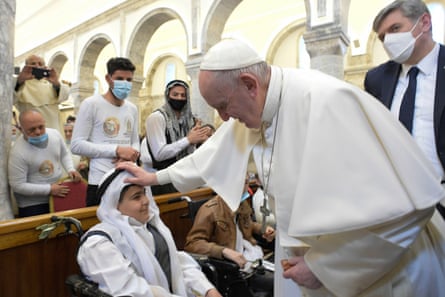 The late Pope Francis holding his hand on the head of a boy in a church.