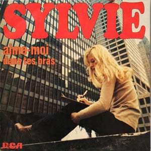 The sleeve of Aime-Moi by Sylvie, showing her sitting in front of a glass-fronted tower block