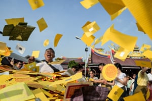 People laugh as they throw pieces of yellow paper into the air