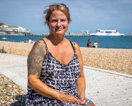Alison Drake sitting on the beach in Dover with the sea behind her