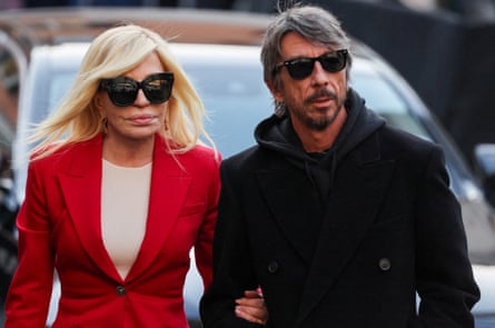 Donatella Versace wears a bright red suit, while Piccioli is dressed in black