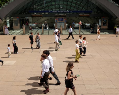 People walk across a plaza in Canary Wharf during a heatwave