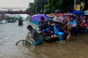 Bangladeshi commuters use a rickshaw to cross a flooded street amid heavy rainfall in Dhaka in July 2017.