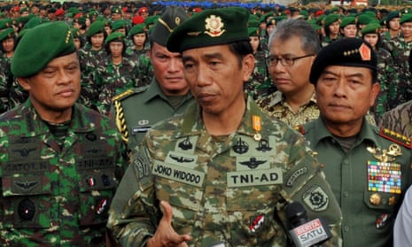 Indonesian President Joko Widodo (C), in full military uniform, standing with Army Chief General Gatot Nurmantyo (L) and Armed Forces Chief General Moeldoko (R) before a formation of female army troops to lead the ceremony of the construction of a military hospital in Jakarta.