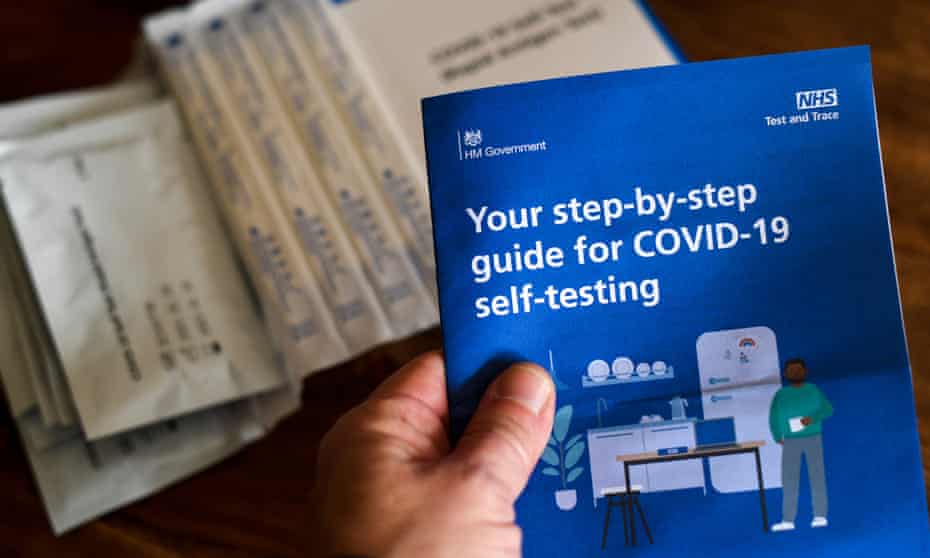 A hand is seen holding a guide for Covid self-testing