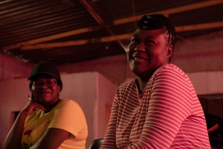 A middle-aged African woman appears happy as she talks while another woman looks on smiling