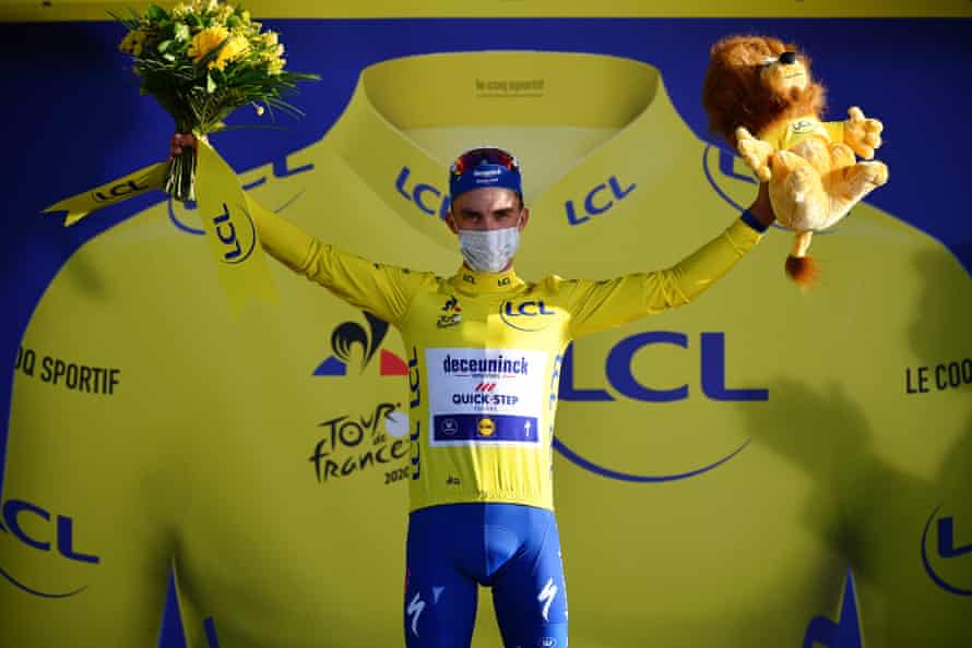 Alaphilippe wears the overall leader’s yellow jersey as he celebrates on the podium.