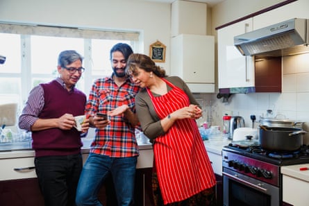 A young adult man in the kitchen with his parents.