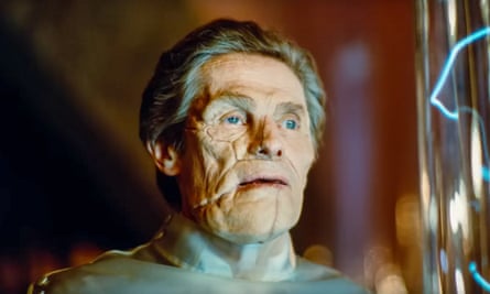 Willem Dafoe, his craggy and cracked face lit up, and wearing a silver collar covering his neck, in his new film Poor Things.