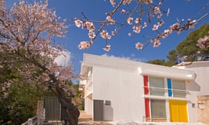 Exterior of the colourful Miró Mallorca Fundació, Palma, surrounded by cherry blossom on a blue-sky day.