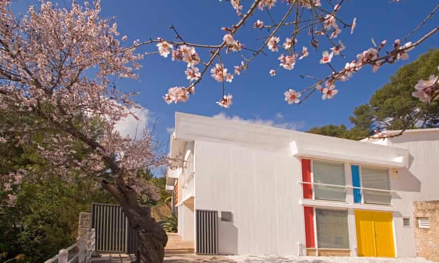 Exterior of the colourful Miró Mallorca Fundació​​, Palma, surrounded by cherry blossom on a blue-sky day.