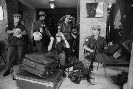 Five UN soldiers in the Ledra Palace hotel, all with caps and in uniform, one sitting next to suitcases with a machine gun propped on his chair