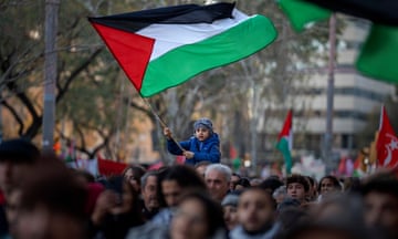 A boy waves a Palestinian flag as demonstrators march during a protest in  Barcelona, Spain