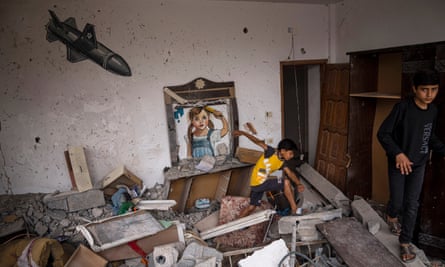 Palestinian children walk past a mural in a destroyed house in Deir al-Balah, Gaza.