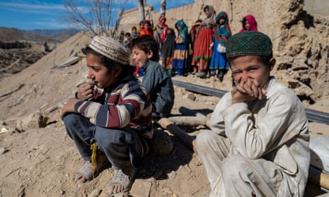 Afghan boys sit outside a house
