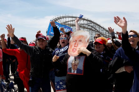 People cheer while holding up trump signs and photos
