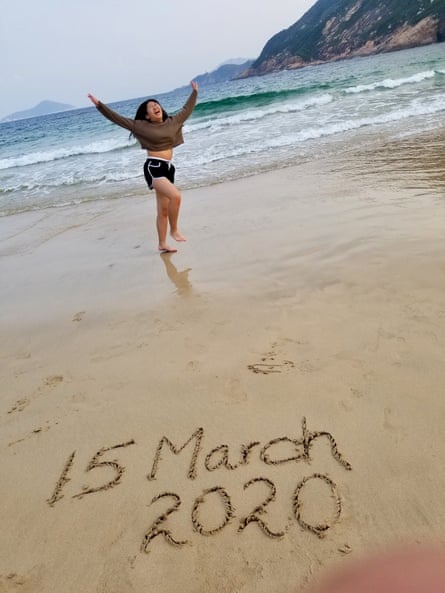 Luna about to do a cartwheel on a sandy beach with “15 March 2020” written in the sand in the foreground, the sea and mountains are in the background