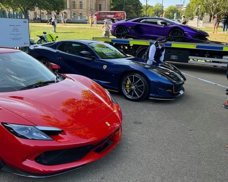 Red and blue Ferrari supercars being inspected by a police officer