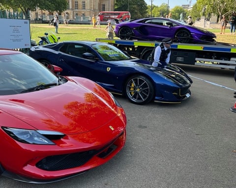 Red and blue Ferrari supercars being inspected by a police officer qhiukiqrihuinv