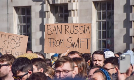 A protester in London holds a placard calling for Russia to be banned from the Swift payment system.