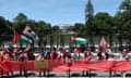 A crowd waves Palestinian flags and unfurls a large red banner in front of the White House.